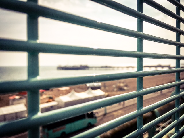 Blurry Brighton Pier seen through the bars of a fence ©Helen Jones-Florio