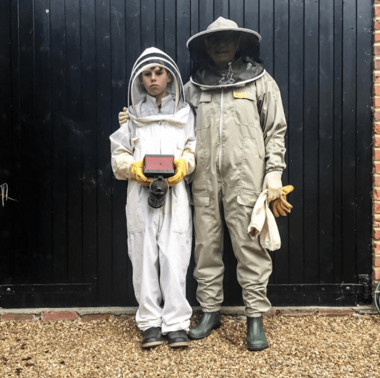 Grandfather Florio with grandson Florio, stand posing in bee-suits, preparing to harvest some Surrey honey, UK © Jason Florio