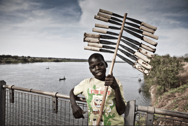 Portrait of a young boy - Knife Vendor' - standing on a bridge in Uganda © Jason Florio
