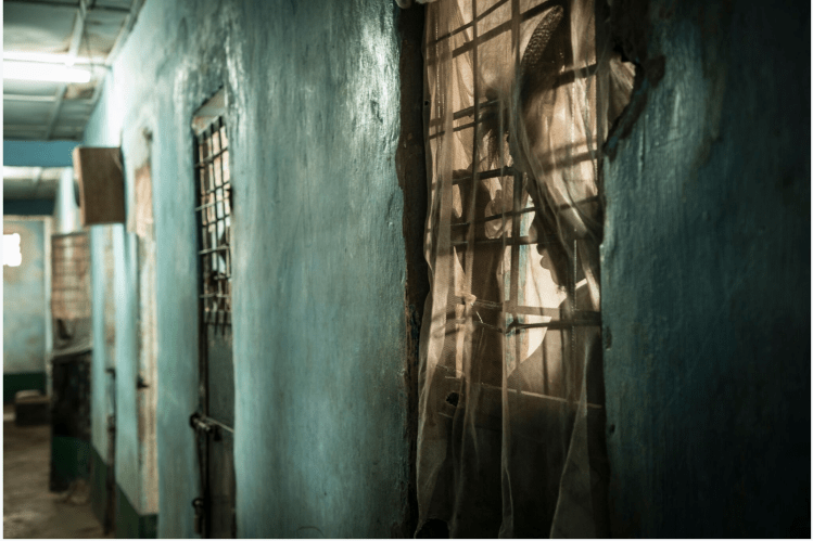 Mile 2 Prison, The Gambia – a prisoner looks out from his cell in the maximum security block– image ©Helen Jones-Florio 
