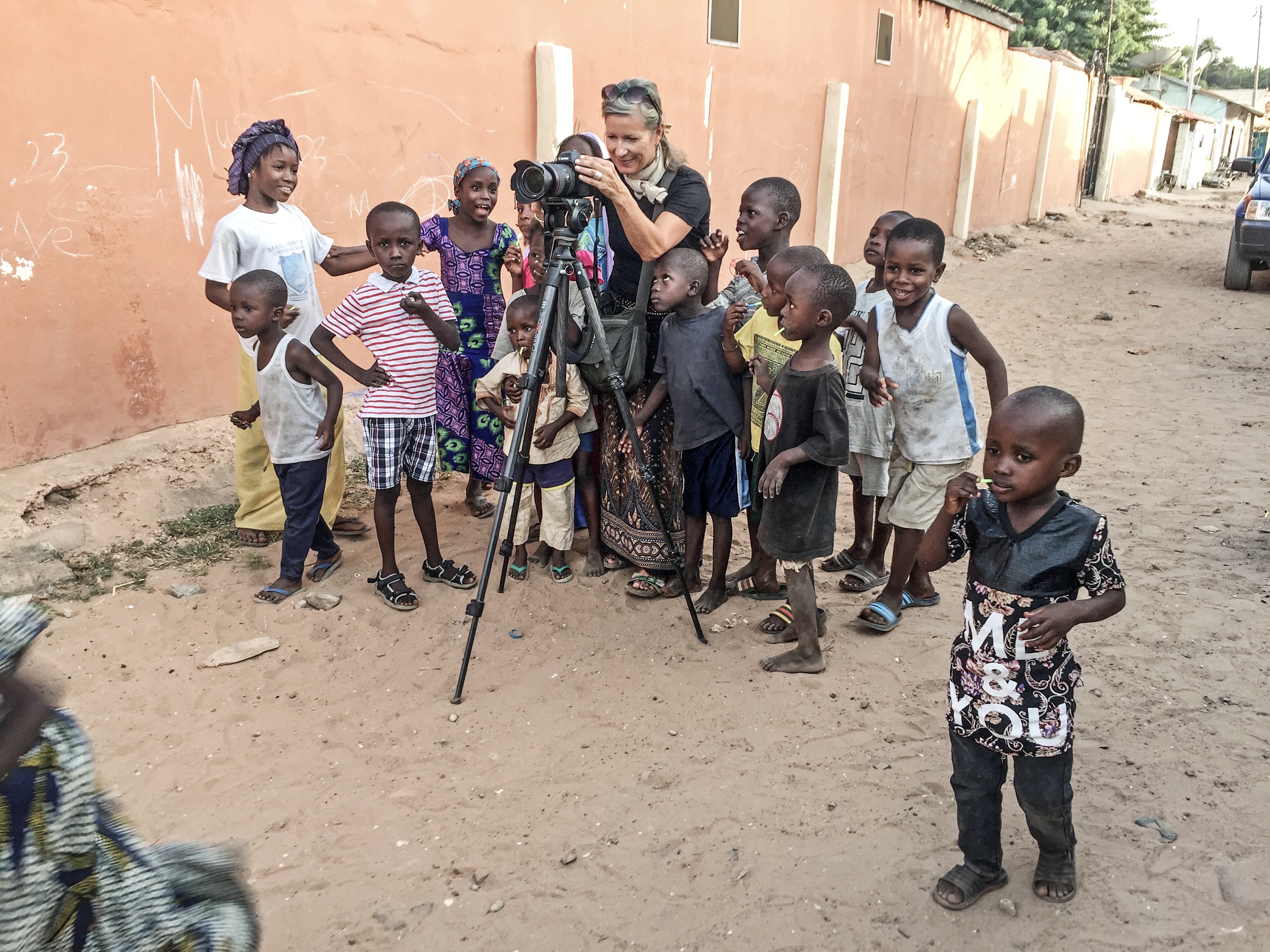 Helen Jones-Florio filming in The Gambia, surrounded by small children © Jason Florio 
