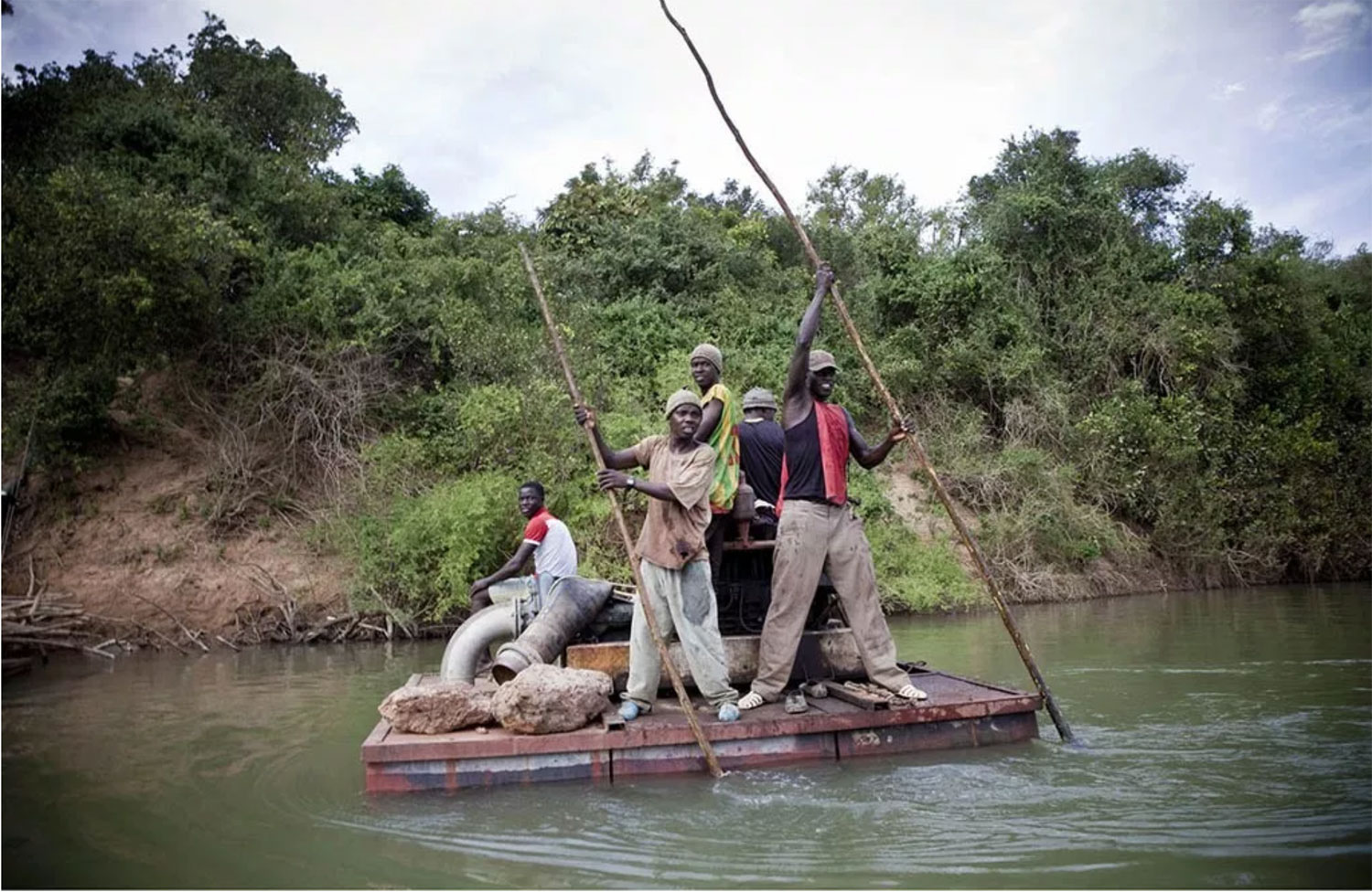 Young men on a float taking a generator to a banana plantation on the River Gambia, Senegal, West Africa © Jason Florio