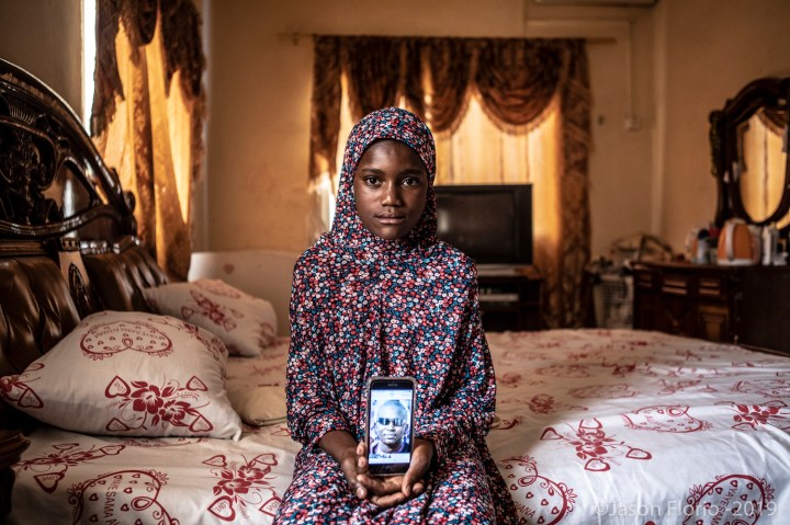 Gambia - victims and resisters: portrait of Bintu Tunkara, daughter of murdered Gambian Lamin Tunkara, holding the only photo she has of him on her mothers cell phone ©Jason Florio