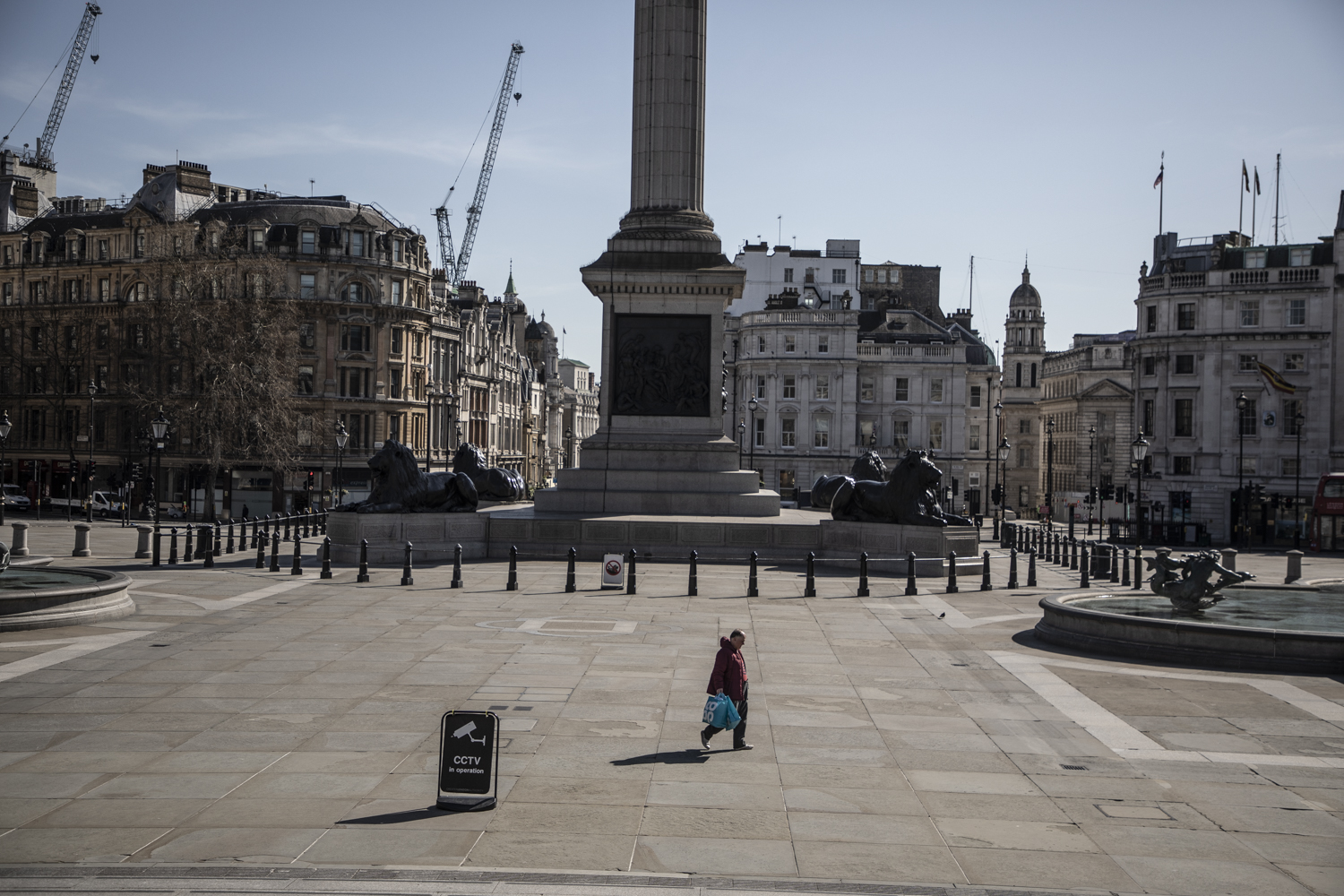 COVID 19 London lockdown. Homelessness - A lone homeless man walks across a deserted Trafalgar Square, London. Image ©Jason Florio