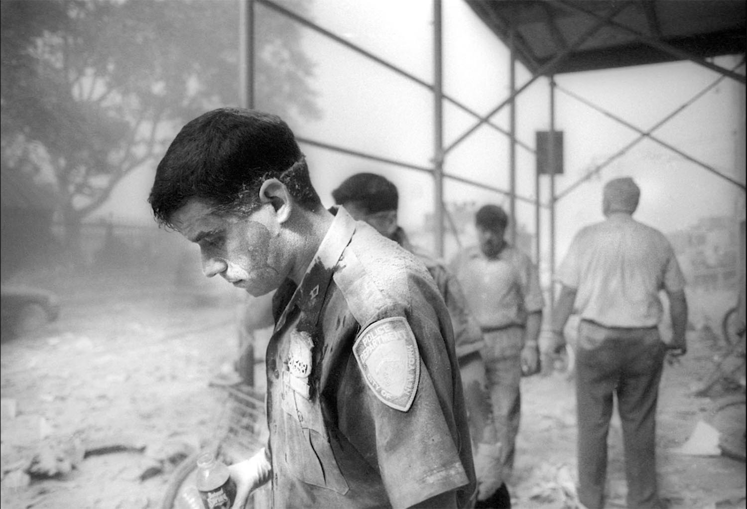 'The Day The Towers Fell - my 9/11 journey' Jason Florio: September 11th, 2001-A New York City cop stands with his head down, among the debris from the fallen World Trade Center Towers, NYC. Black and white image ©Jason Florio
