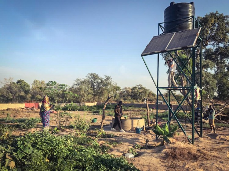 Photographer and filmmaker, Jason Florio, stands high up on a water tower to photograph a female farmer, Basse, The Gambia, West Africa. Image © Helen Jones-Florio