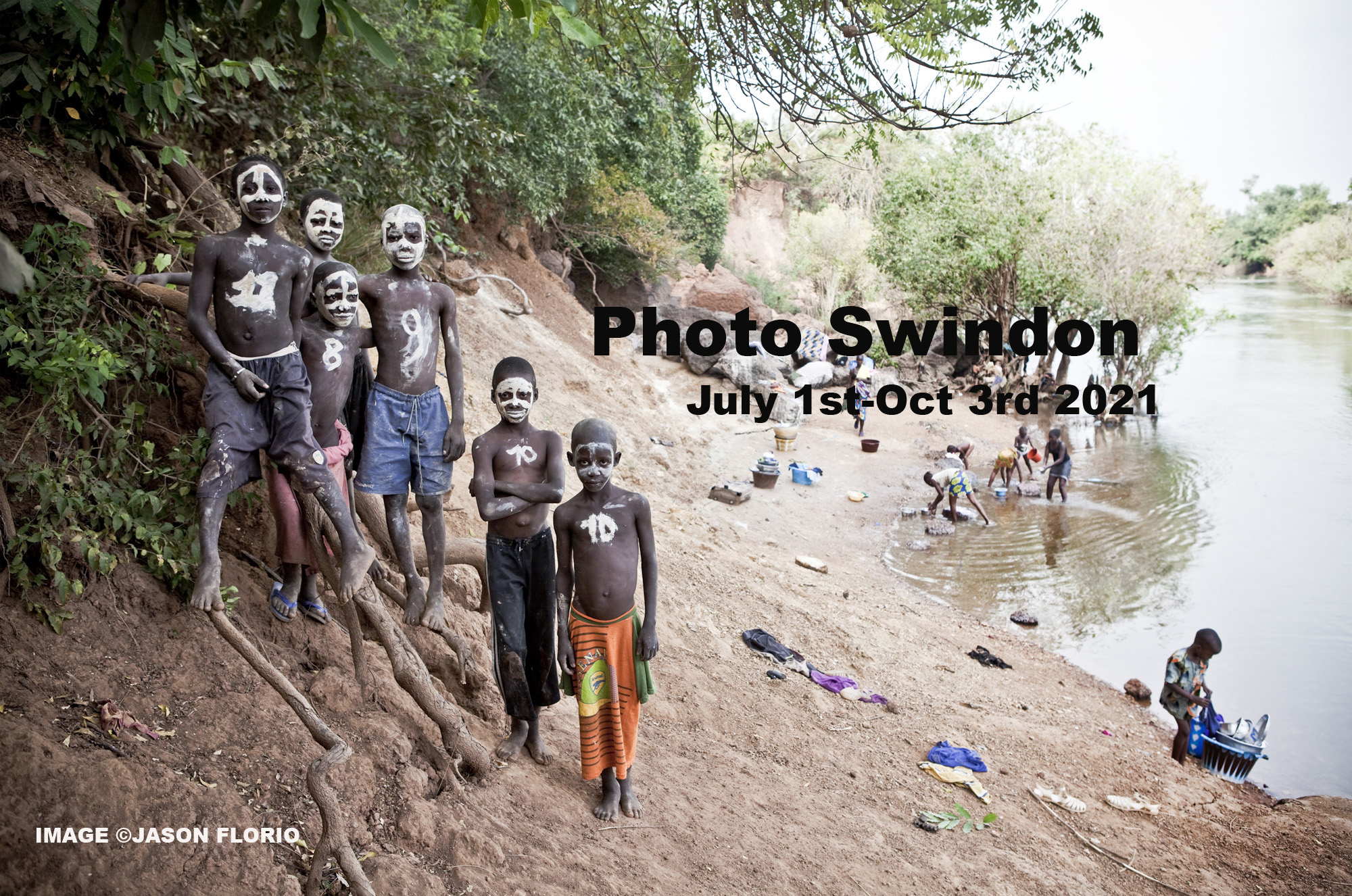 Photo Swindon International Photography Exhibition - 1st July-3rd October, 2021. Boys with painted faces stand looking at the camera, by the River Gambia, West Africa - advertisement for Photoswindon photo exhibition. Image ©Jason Florio
