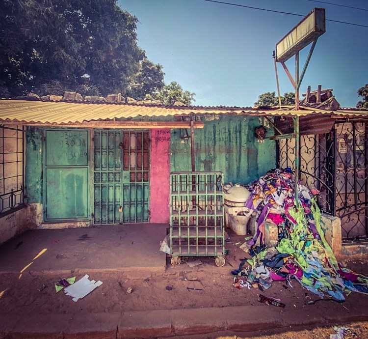 #GambiaDoors - the closed frontage of a tailor shop with a pile of remnant fabric, and an old toilet, Bakau, The Gambia. Image ©Helen Jones-Florio