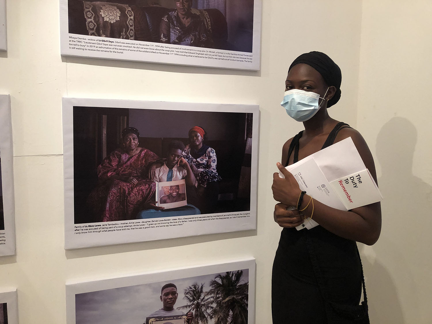 Opening of 'Memory House', The Gambia, West Africa. A young Gambian woman stands in front of a portrait of herself with her family. Images ©Jason Florio & Helen Jones-Florio from 'Gambia - victims, and resisters'