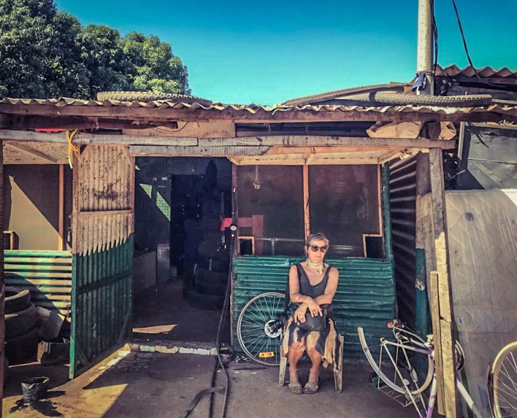 Photographer/videographer, Helen Jones-Florio, sits outside a local car repair shop, The Gambia. Image courtesy of Jason Florio