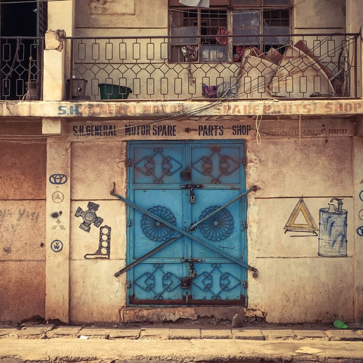 #GambiaDoors - the (un)mundane doors and storefronts of The Gambia, West Africa. A blue metal closed doors of a store. Image ©Helen Jones-Florio