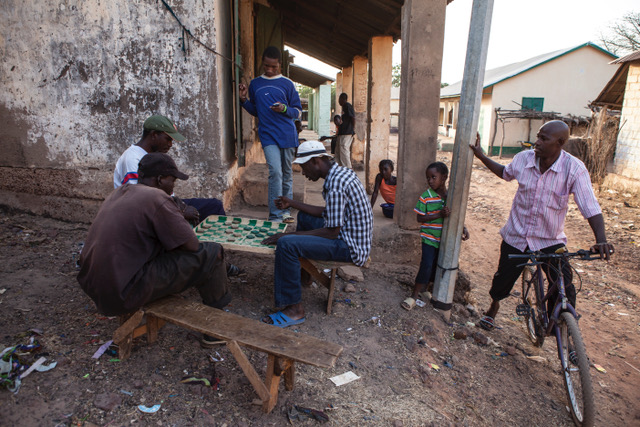 Photo of the Day: Men play a board game in the streets of Fatoto, The Gambia, watched by children. Image ©Jason Florio