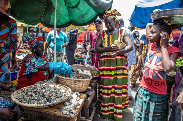 A woman selling oysters from her harvest, in a busy market, The Gambia, West Africa