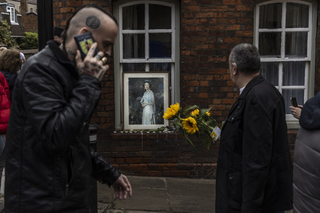 A portrait of Queen Elizabeth the second, in a window on a street next to Windsor Castle the day following her death. People flocked to Windsor to pay their respects and leave flowers next to the castle gates. Image ©Jason Florio