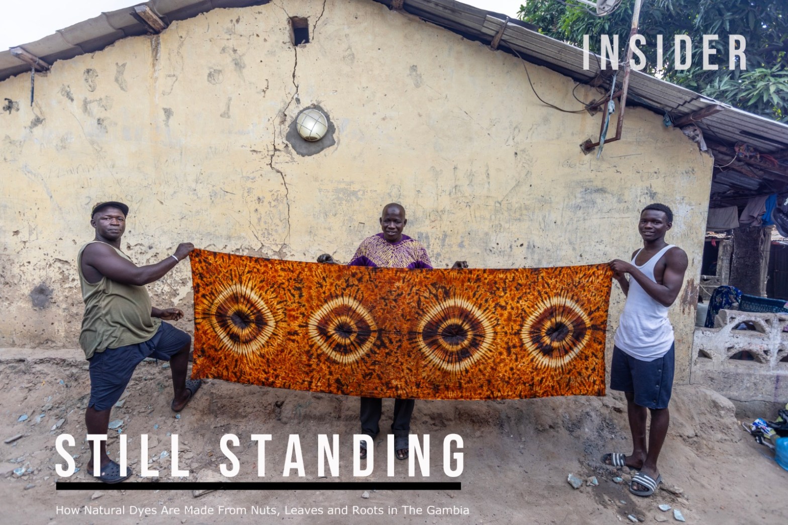 Gambian artisan, Musa Jaiteh (centre) holding a sample of fabric which he has tie-dyed. Image © Jason Florio, The Gambia Nov 2022