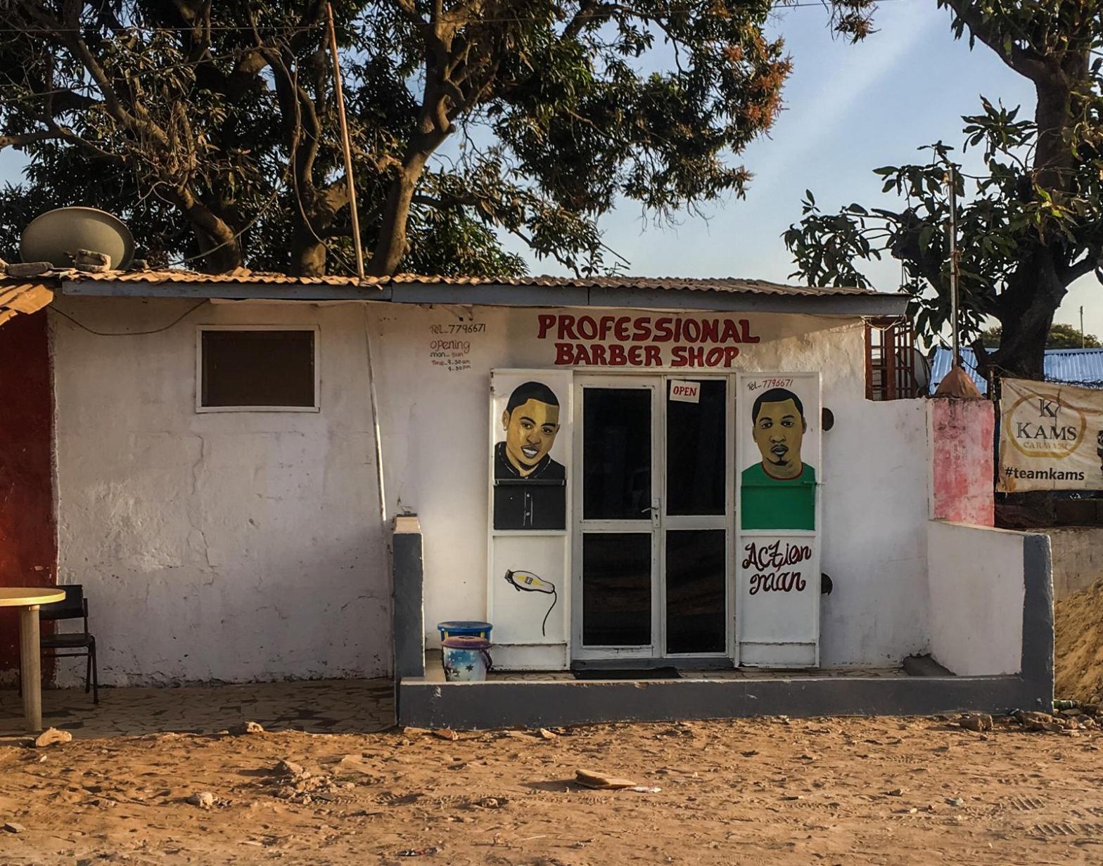 Urban barber shop exterior with hand painted signs - The Gambia, West Africa